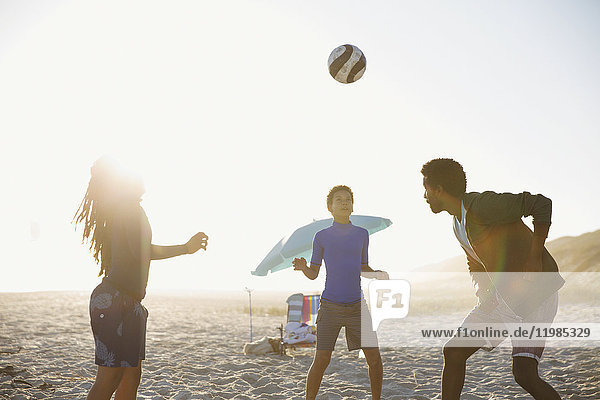 Family playing soccer on sunny summer beach