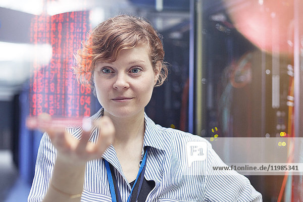 Female IT technician holding futuristic digital tablet in server room