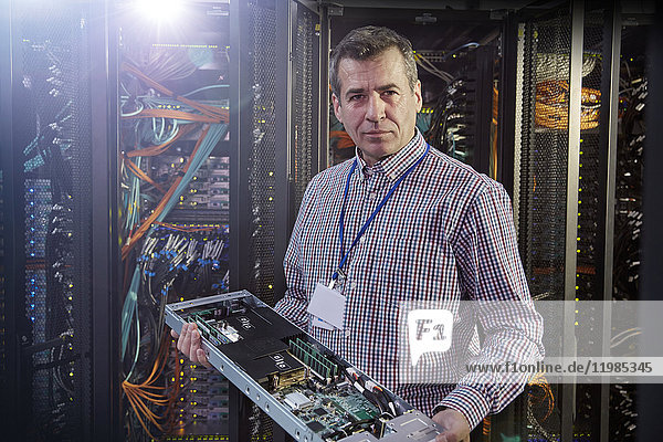 Portrait male IT technician holding panel in server room