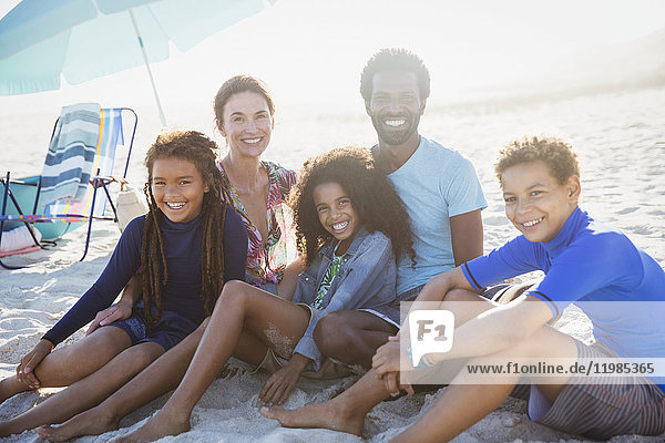Portrait lächelnde multiethnische Familie am sonnigen Sommerstrand