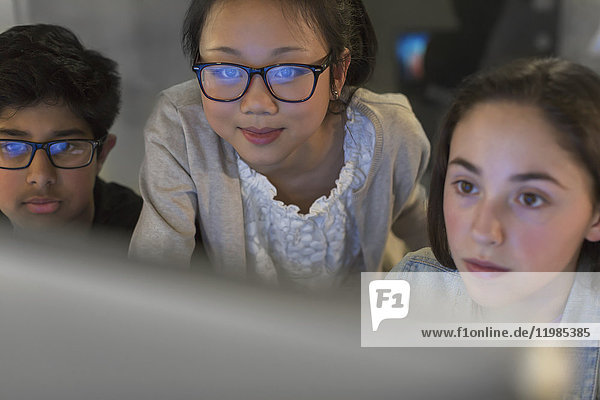 Fokussierte Schüler mit Computer im dunklen Klassenzimmer