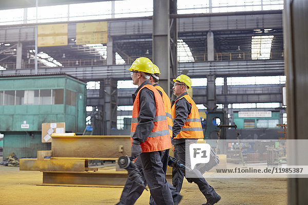 Männliche Arbeiter  die in der Stahlfabrik spazieren gehen