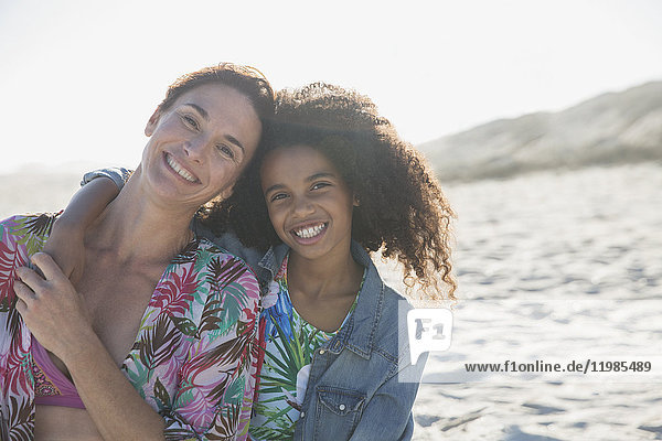 Portrait smiling  confident mother and daughter hugging on sunny  summer beach