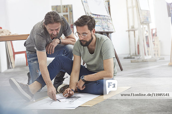 Männliche Künstler beim Skizzieren auf dem Boden im Atelier der Kunstklasse