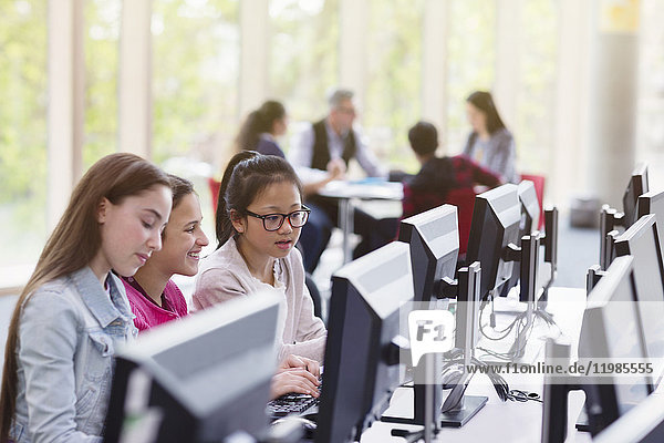 Schülerinnen studieren am Computer in der Bibliothek