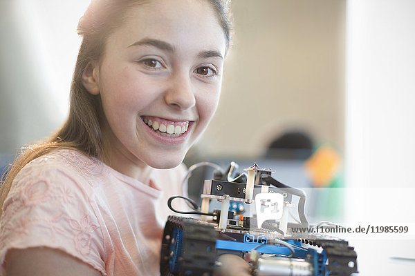 Portrait lächelndes  selbstbewusstes Mädchen  das einen Roboter hält