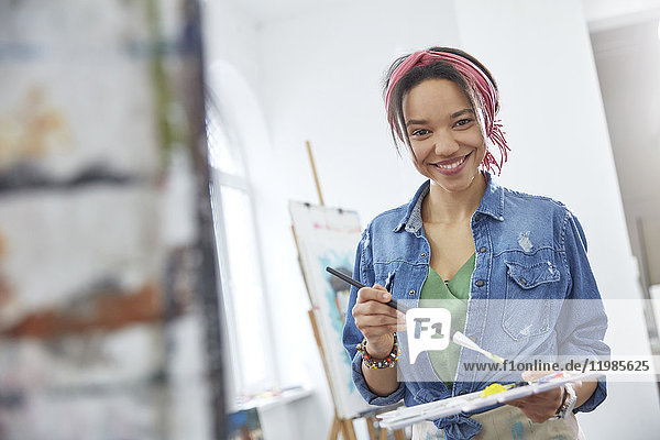 Portrait lächelnde Künstlerin mit Pinsel und Palette  Malerei im Atelier der Kunstklasse