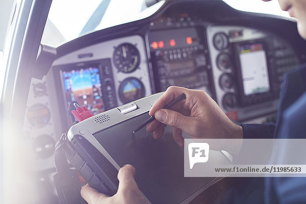 Flugzeugpilot mit Stylus auf digitalem Tablett im Cockpit