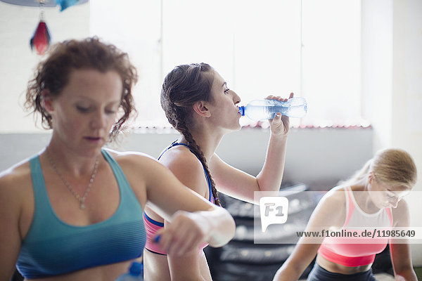 Young women drinking water and resting post workout in gym