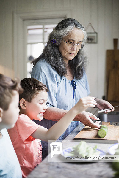 Großmutter und Enkel beim Gurkenschneiden in der heimischen Küche