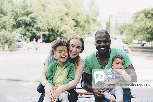 Portrait of happy parents with children sitting at park
