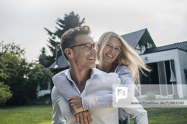 Ein glückliches Paar  das sich im Garten seines Landhauses umarmt.