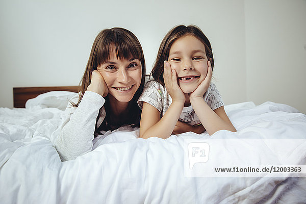Portrait of happy mother and daughter in bed