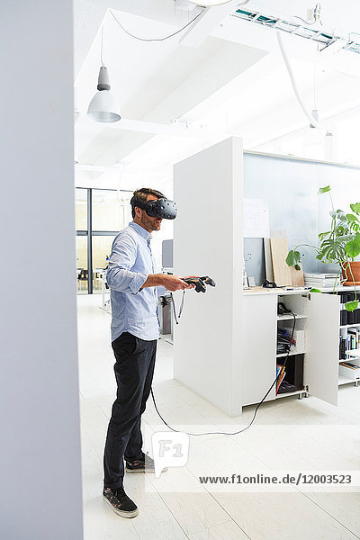 Businessman using virtual reality stimulator while standing in creative office