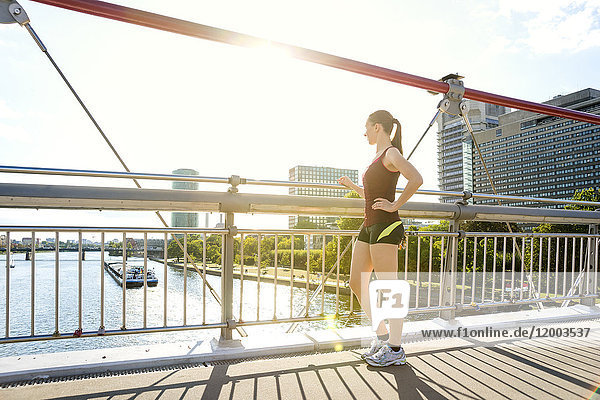 Deutschland  Frankfurt  sportliche junge Frau auf der Brücke stehend