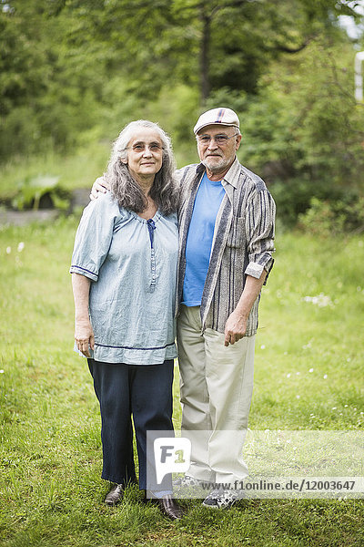 Portrait of senior couple standing on grass in back yard