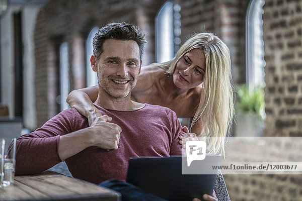 Glückliches Paar in der Landhausküche mit Blick auf den Laptop