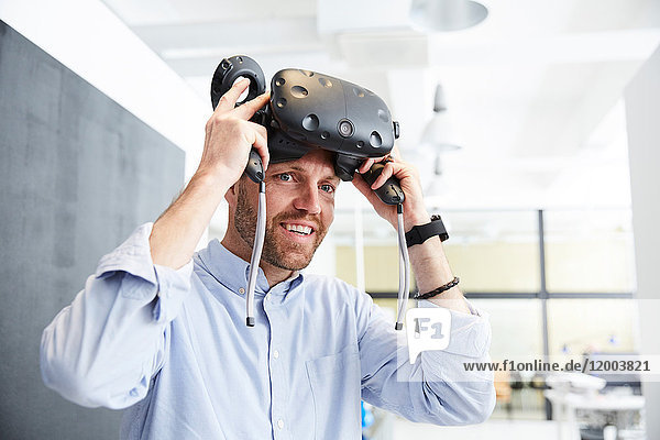 Smiling businessman wearing virtual reality stimulator at creative office