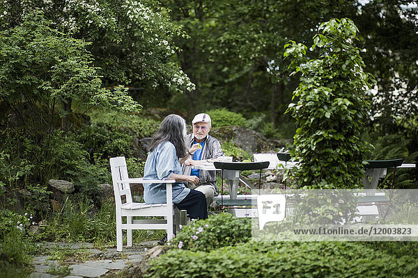 Seniorenpaar beim Mittagessen am Tisch im Hinterhof