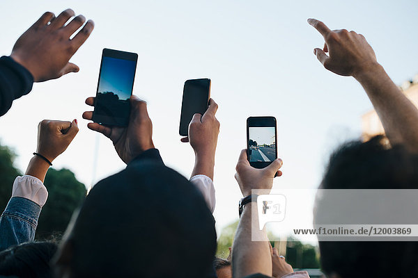 Low-Winkel-Ansicht von Freunden die von Smartphones aus gegen den Himmel fotografieren.