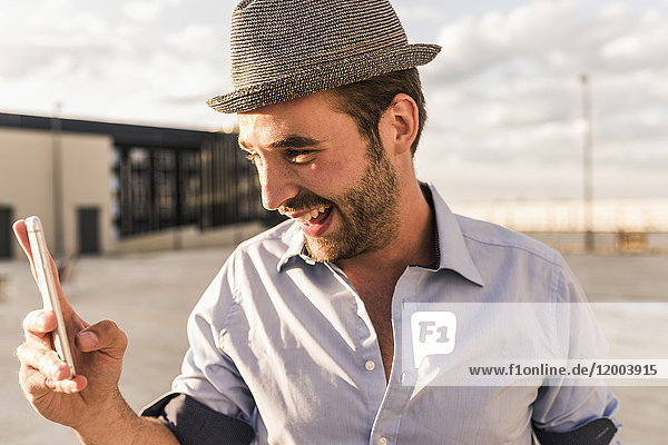 Happy young man with cell phone on rooftop