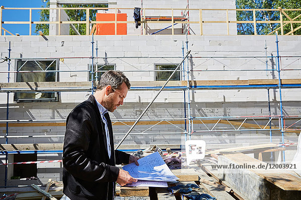 Seitenansicht des Architekten beim Lesen des Bauplans bei unvollständigem Bauen auf der Baustelle