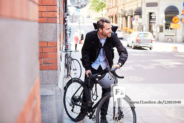 Businessman with bicycle on street in city during sunny day