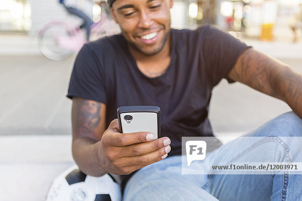 Smiling young man looking at smartphone  close-up