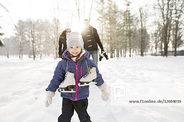 Kleines Mädchen beim Schlittschuhlaufen mit ihren Eltern