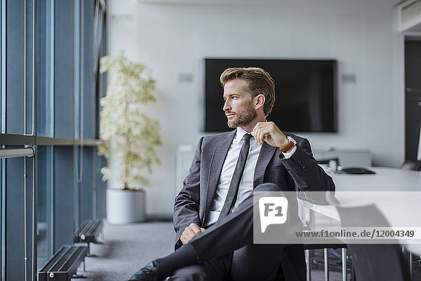 Businessman sitting in conference room looking out of the window
