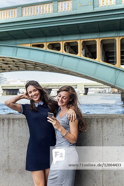 UK  London  zwei Frauen mit Smartphone am Ufer der Themse