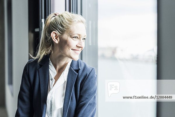 Smiling businesswoman looking out of window