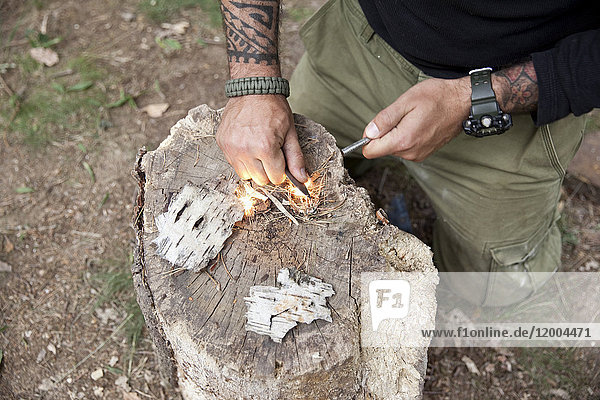 Man igniting a fire on tree stump in the forest