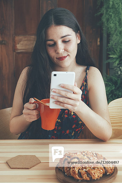 Freckled junge Frau mit Kaffeetasse mit Smartphone