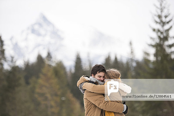 Glückliches junges Paar umarmt sich in der Winterlandschaft