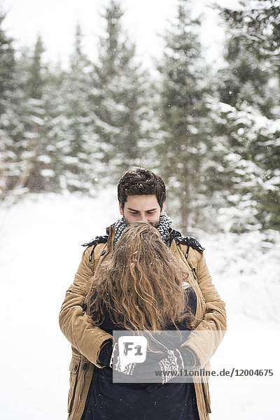 Glückliches junges Paar umarmt sich in der Winterlandschaft