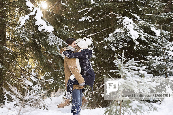Glückliches junges Paar von Angesicht zu Angesicht im schneebedeckten Winterwald