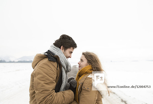 Verliebtes junges Paar auf der Landstraße in schneebedeckter Landschaft