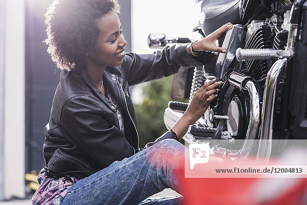 Junge Frau bei der Wartung ihres Motorrads