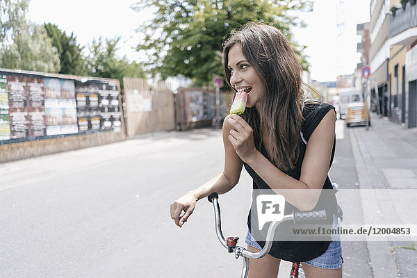 Woman with bicycle eating ice lolly