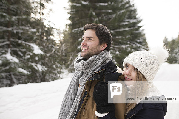 Happy young couple in snow-covered winter forest