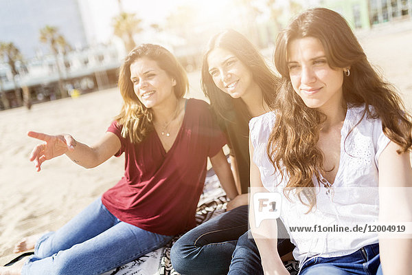 Drei glückliche Freundinnen sitzen am Strand