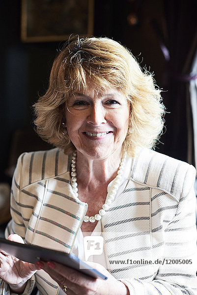 Porträt einer lächelnden Senior-Geschäftsfrau mit Tablette