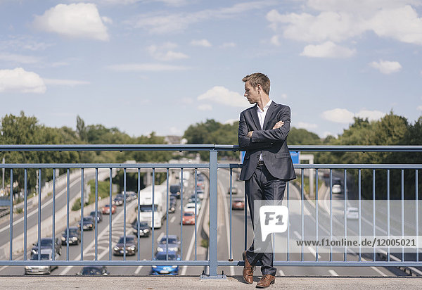 Businessman standing on a bridge over a motorway