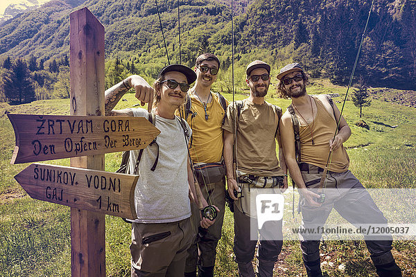 Slovenia  Bovec  four anglers posing at signpost on meadow near Soca river