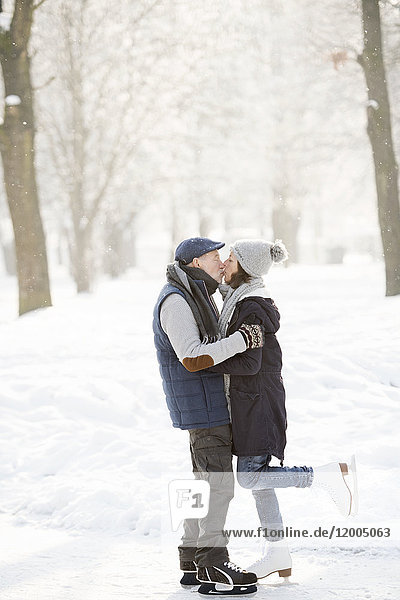 Senior couple hugging and kissing on frozen lake