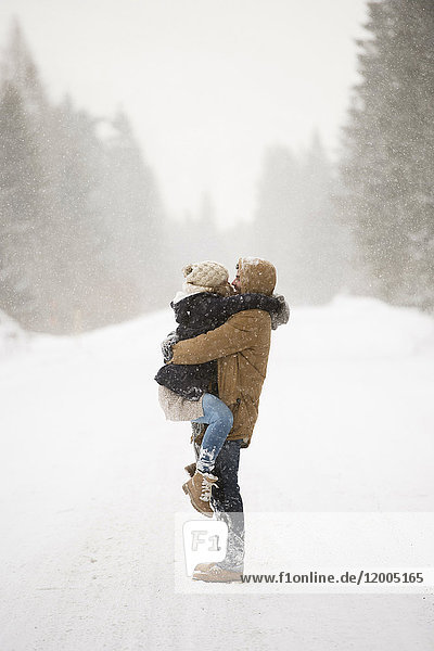 Glückliches junges Paar von Angesicht zu Angesicht in verschneiter Winterlandschaft
