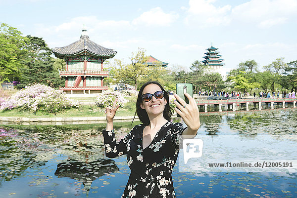 Südkorea  Seoul  Frau  die ein Selfie mit Smartphone im Gyeongbokgung Palace nimmt