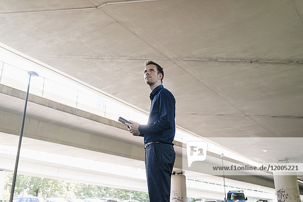 Businessman standing at underpass holding tablet