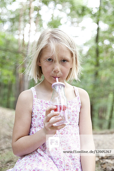 Mädchen beim Trinken aus einem Glas Wasser im Wald